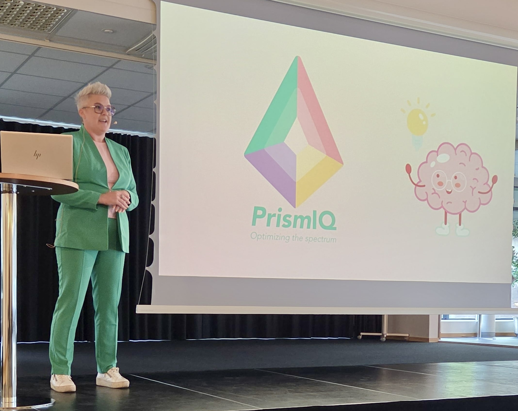 Föreläsning framför en presentation med PrismIQs logotyp